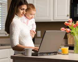 Mother Using Computer, Baby in Arm